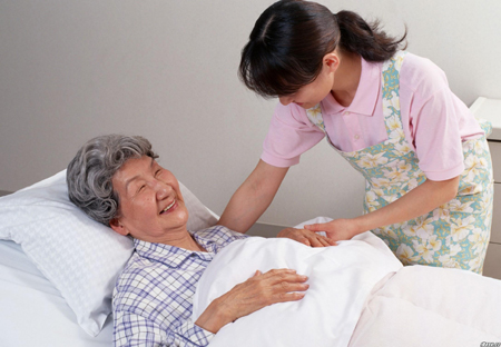 Dịch vụ chăm sóc người bệnh Bảo Việt với nhân viên đang ân cần đắp chăn cho bà ngủ